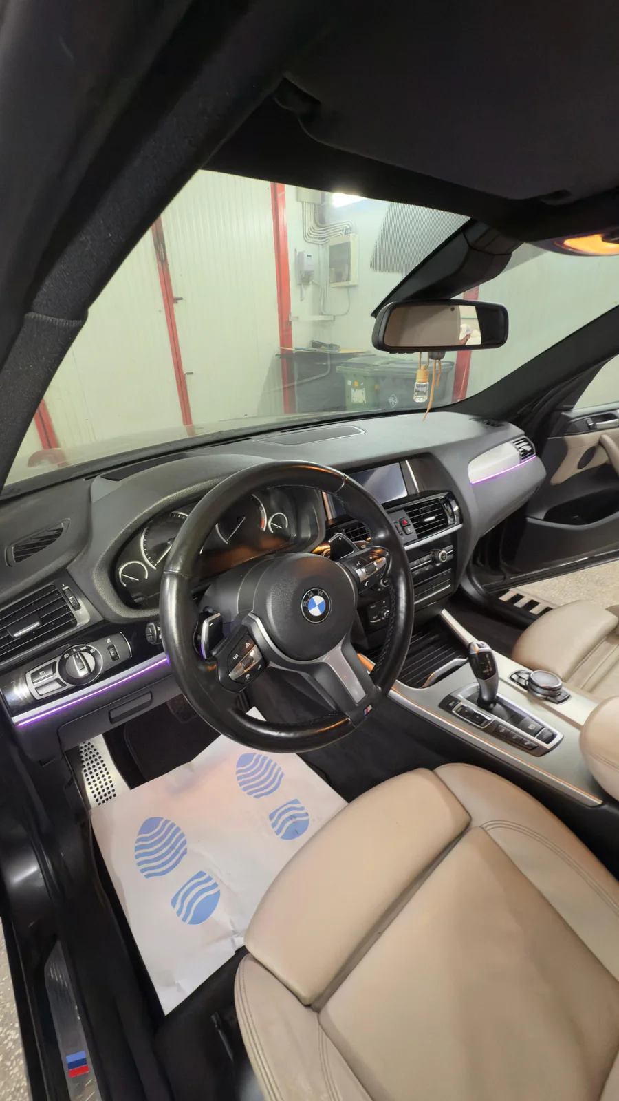 Habitaclu BMW cu scaune din piele crem și protecție pentru covoraș.